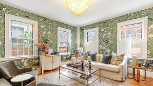 A living room with floral wallpaper, a chandelier, a sofa, and a coffee table.