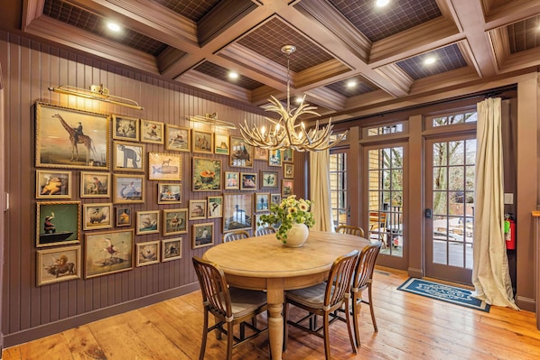 A dining area with a round table, wooden chairs, and a chandelier.