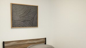 Ein Schlafzimmer mit einem Bett, einem Deckenventilator, Wandkunst und einem Nachttisch.