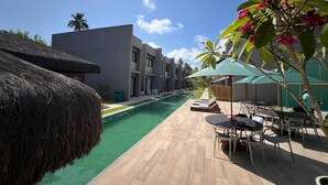 Ein Poolbereich mit Holzterrasse, Liegestühlen und Sonnenschirmen.