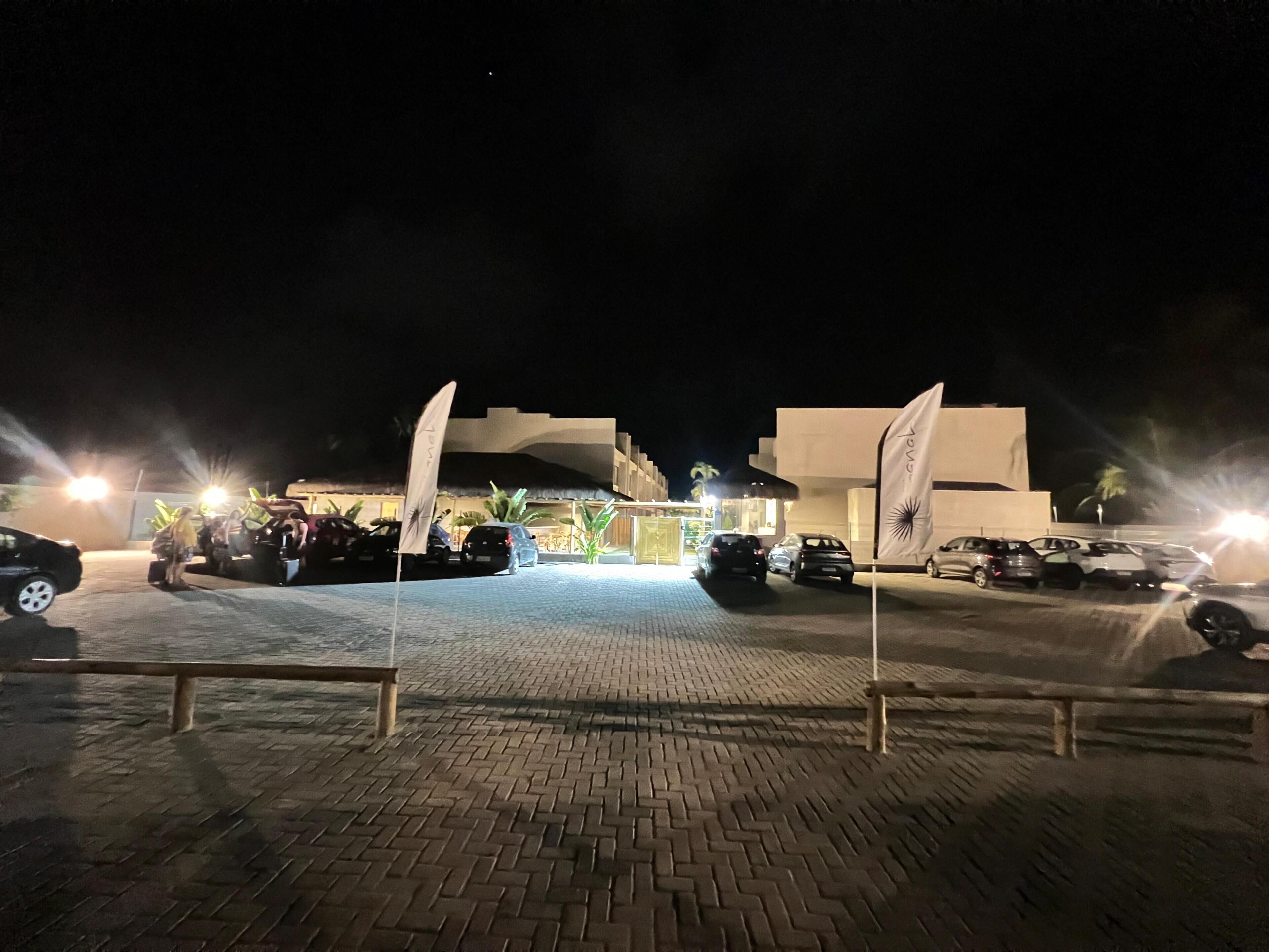 A nighttime parking area with cars and a building in the background.