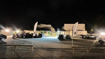 A nighttime parking area with cars and a building in the background.