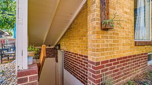 A brick house with a porch, a window, and a potted plant.