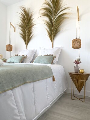 Restful retreat with a large bed, side table, and a beautiful plant above.