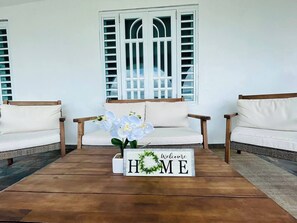 A room with two white sofas, a wooden coffee table, and a window with white shutters. - Solar Powered Near Ferry to Culebra (Ceiba)