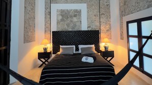 A bedroom with a bed, two bedside tables with lamps, a ceiling fan, and a window with a view. - Casa Shakti a paradise in the city (Mérida)