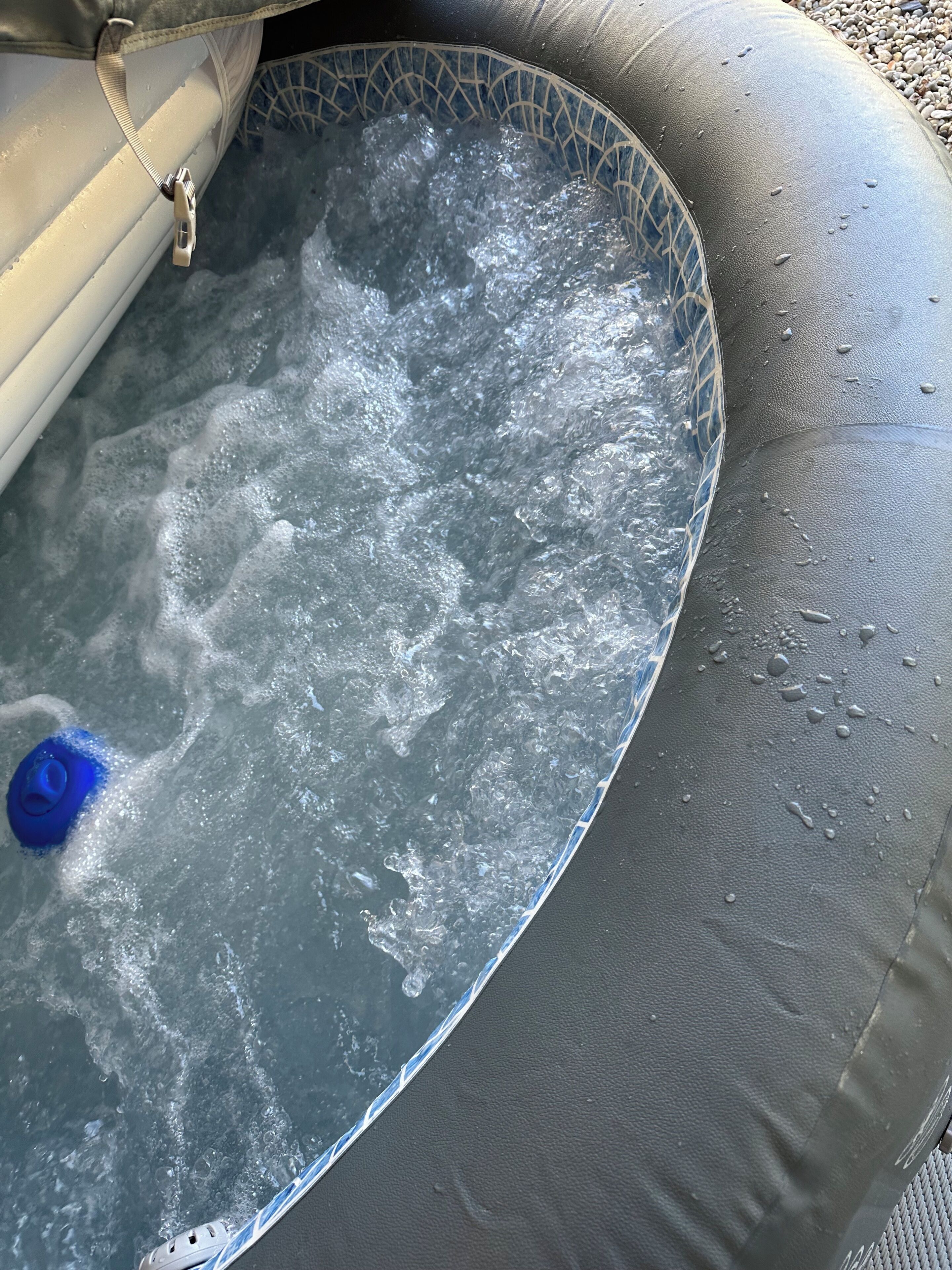 Een opblaasbaar bubbelbad met een blauwe pomp en een ketting.