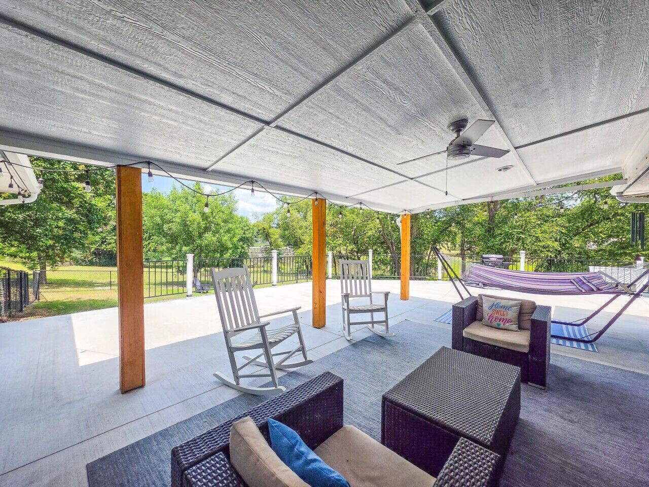 Een terras buiten met zitplaatsen, een hangmat en uitzicht op begroeiing.