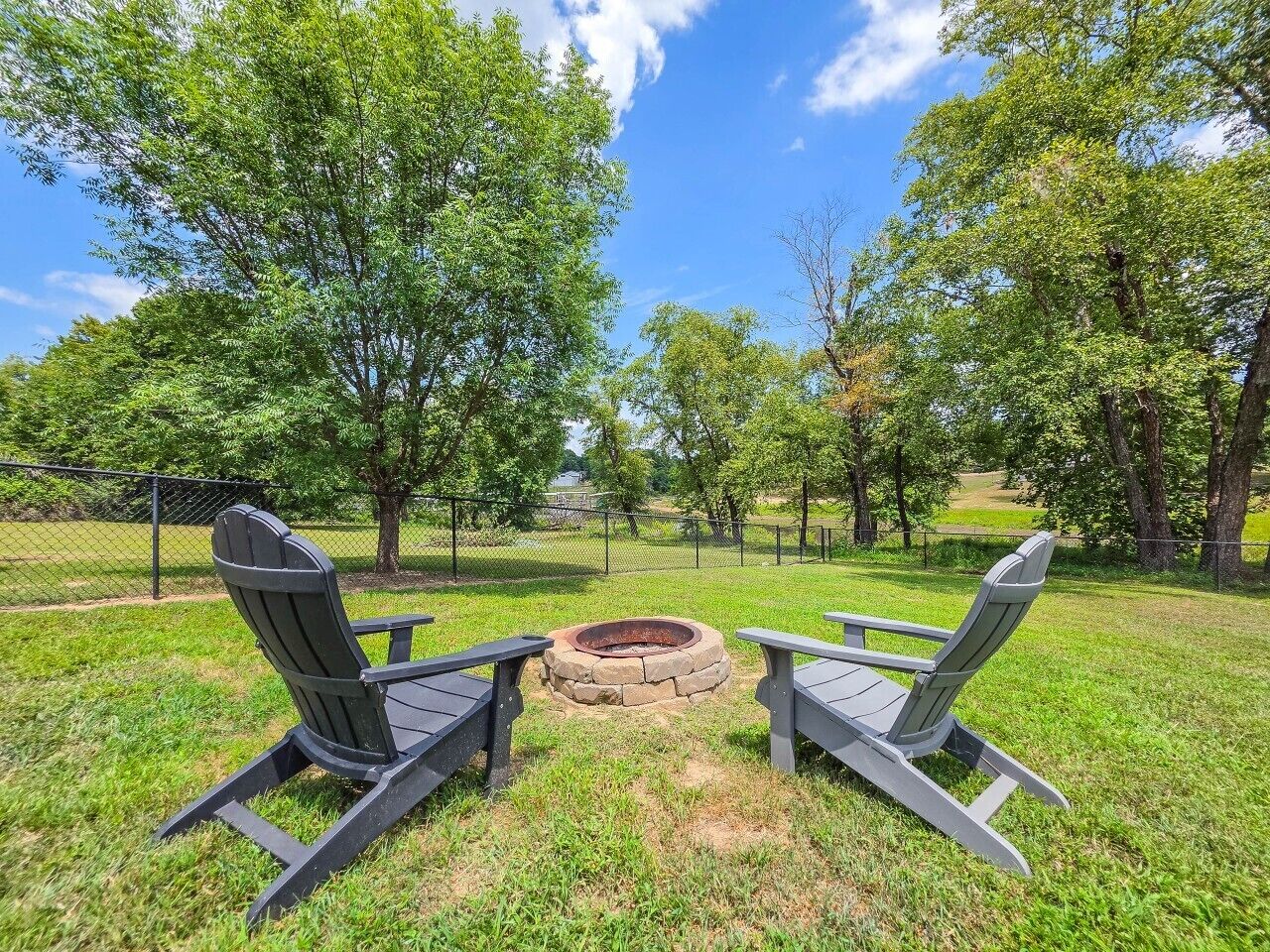 Un espace extérieur aménagé avec des chaises Adirondack et un foyer en pierre.
