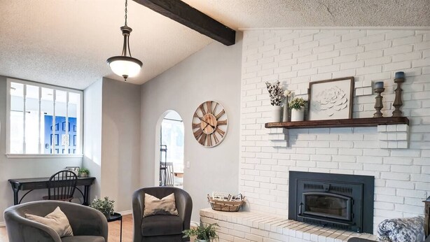 Una sala de estar con chimenea, dos sofás, una mesa de centro y un reloj en la pared.