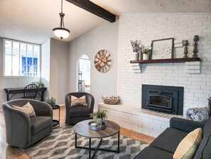 Un salon avec une cheminée, deux canapés, une table basse et une horloge au mur.