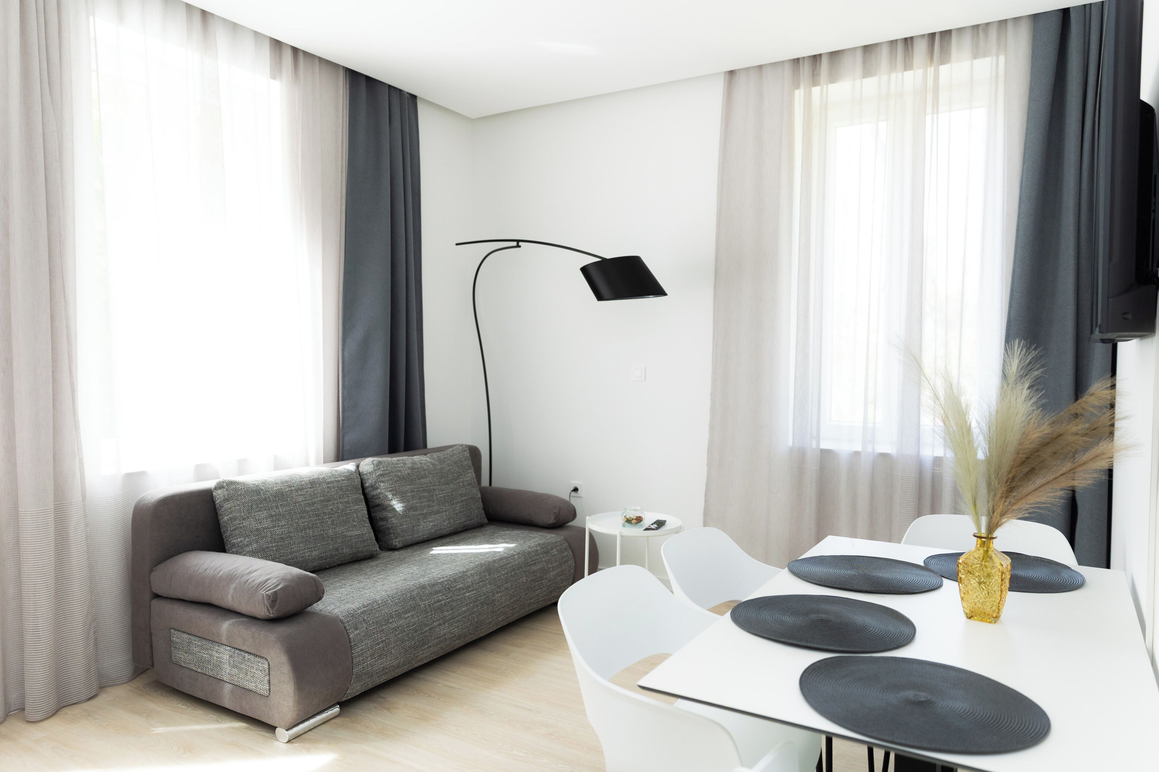 Una sala de estar moderna con un sofá, una mesa de comedor y una lámpara de pie.