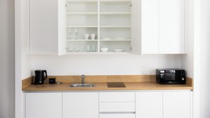 Une cuisine moderne avec des meubles blancs, un plan de travail en bois, une machine à café, un grille-pain et un four à micro-ondes.