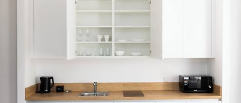 Eine moderne Küche mit weißen Schränken, einer Holzausziehtafel, einer Kaffeemaschine, einem Toaster und einer Mikrowelle.