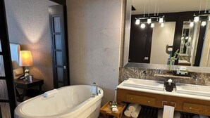 A modern bathroom with a freestanding bathtub, a vanity with dual sinks, and a large mirror.