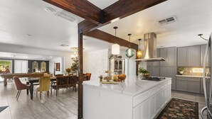 A spacious kitchen with a large island, modern appliances, and a dining area with a pool table.