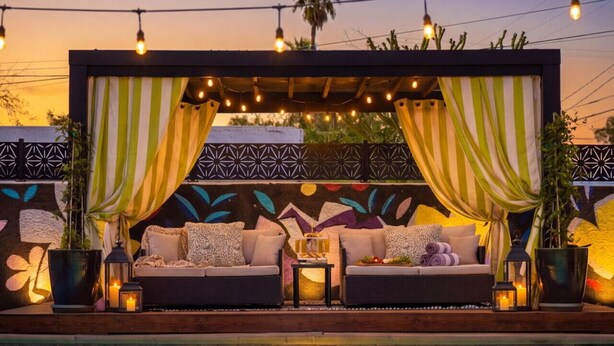 A poolside lounge with a sofa, cushions, and ambient lighting.