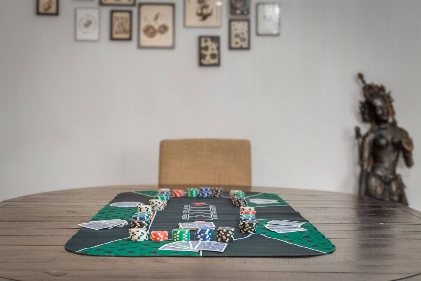 Une table de poker, avec des jetons et des cartes, est installée sur une table en bois recouverte d’un tapis vert.