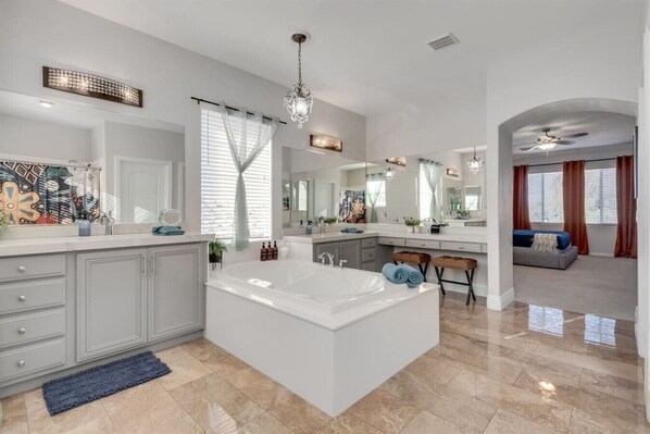 A spacious bathroom with a large bathtub, a vanity with a mirror, and a shower area.