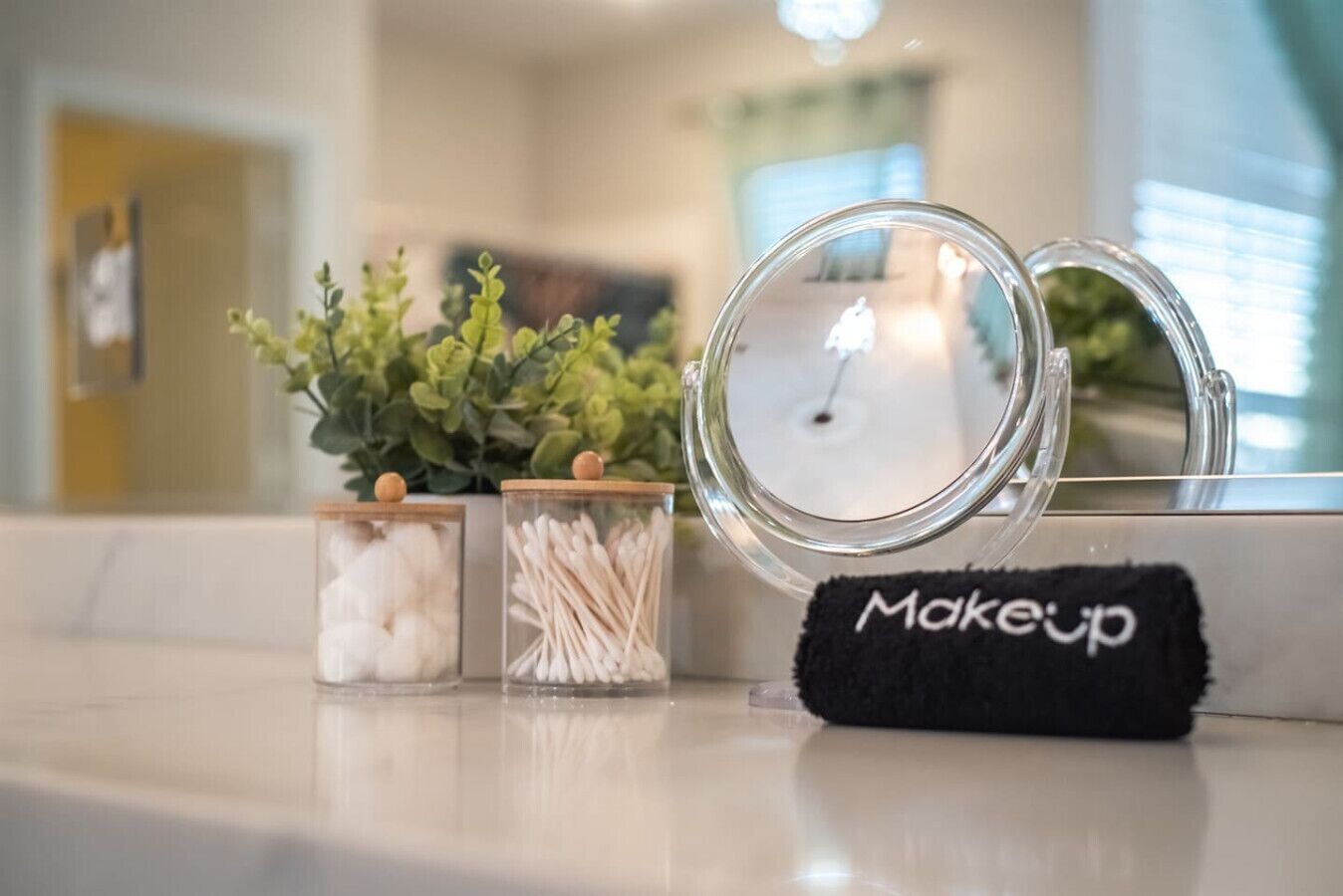 Un coin beauté équipé de pots de cotons et de bâtonnets en coton, d’un miroir et d’une serviette portant l’inscription « Maquillage ».