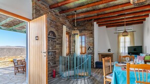 A rustic interior with stone walls, wooden beams, a dining area with a table and chairs, and a view of the outdoors. - Holiday Home 'Archontiko Keli' with Mountain View, Wi-Fi and Air Conditioning (Katakilos)