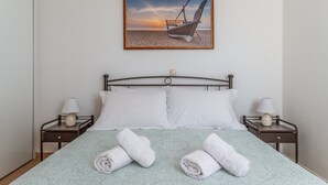 A neatly made bed with white linens, two bedside tables with lamps, and a framed picture of a boat on the wall. - Holiday Home 'Archontiko Keli' with Mountain View, Wi-Fi and Air Conditioning (Katakilos)