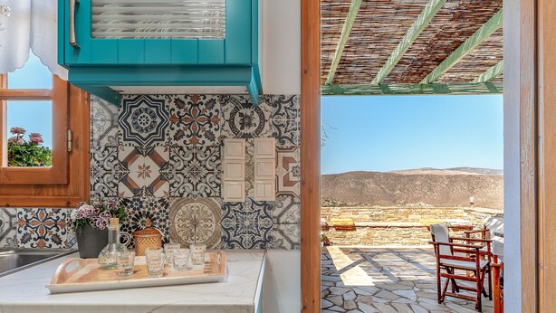 A kitchen with a tiled backsplash, a countertop with glassware, and a view of an outdoor patio with a table and chairs. - Holiday Home 'Archontiko Keli' with Mountain View, Wi-Fi and Air Conditioning (Katakilos)