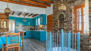 A kitchen with teal cabinets, a wooden dining table, and a blue playpen. - Holiday Home 'Archontiko Keli' with Mountain View, Wi-Fi and Air Conditioning (Katakilos)