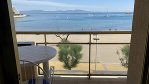 A balcony with a view of the sea, a sandy beach, and distant mountains. - Apartment 'Platja Mar 2' with Sea View and Balcony (L'Escala)