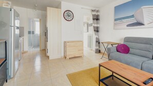 A modern living room with a grey sofa, a wooden coffee table, and a painting of a beach scene.