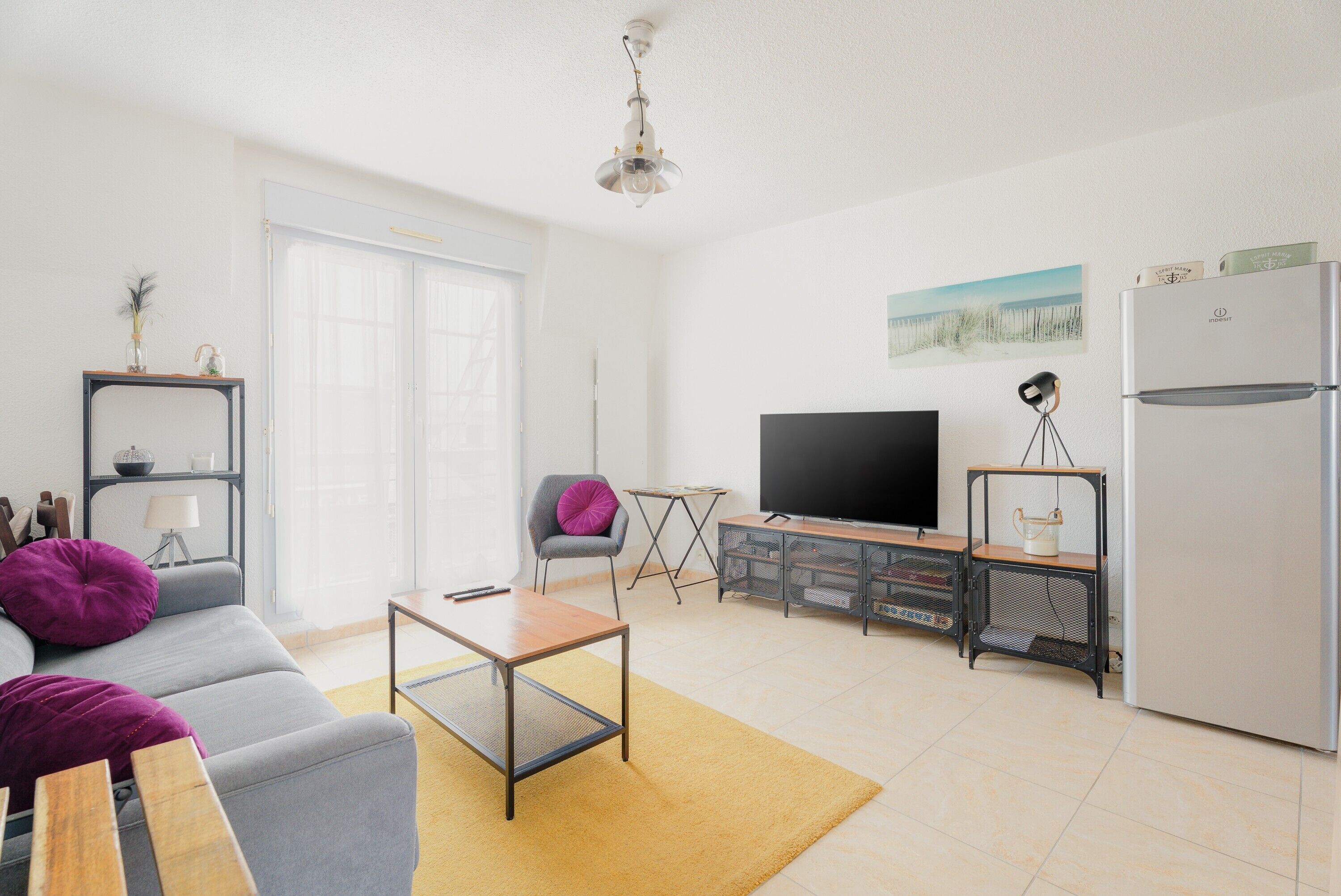 Ein modernes Wohnzimmer mit einer Couch, einem Couchtisch, einem Fernseher und einem Kühlschrank.