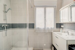 A bathroom with a shower, a sink, and a mirror. - Apartment 'Le Saint Martin' with Sea View, Balcony and Wi-Fi (Bréhal)