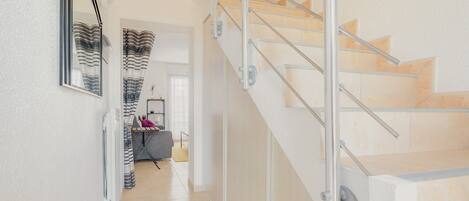 Una escalera con barandillas de metal, un espejo en la pared y una puerta que da a otra habitación.
