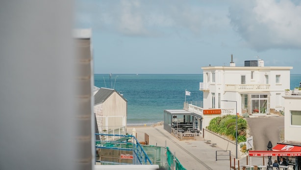 A coastal building with a view of the sea, a flag, and a sign reading 'LA VIECI'.