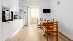 A modern kitchen with white cabinets, a stove, and a dining area with wooden chairs and a table. - Holiday Home 'Diga' with Mountain View, Wi-Fi and Air Conditioning (Palermo)