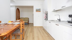 A modern kitchen with white cabinets, a wooden dining table, and a bench. - Holiday Home 'Diga' with Mountain View, Wi-Fi and Air Conditioning (Palermo)