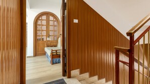 A wooden staircase with a handrail, a door leading to a room with a bed and a chair, and a window with a view of the outside. - Holiday Home 'Diga' with Mountain View, Wi-Fi and Air Conditioning (Palermo)