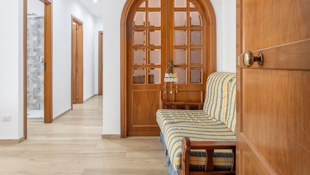 A hallway with wooden doors, a bed with striped bedding, and a bench. - Holiday Home 'Diga' with Mountain View, Wi-Fi and Air Conditioning (Palermo)