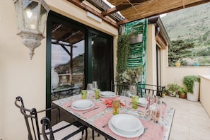 A dining table set for four with chairs, a patterned tablecloth, and various glassware.