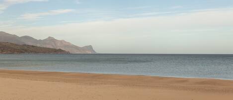 A beach with a clear view of distant mountains.