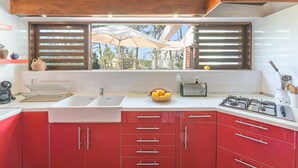 A kitchen with a sink, stove, and red cabinets. - Apartment 'Cerca Do Altinho' with Private Pool, Private Terrace and Wi-Fi (Vila Nova de Milfontes)