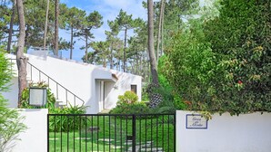 A white building with a black gate, surrounded by greenery and trees. - Apartment 'Cerca Do Altinho' with Private Pool, Private Terrace and Wi-Fi (Vila Nova de Milfontes)