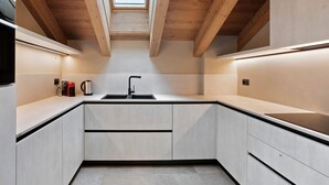 Une cuisine moderne dotée d’une verrière, de poutres en bois et d’un plan de travail noir.