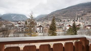 A town with a prominent church tower, surrounded by residential buildings and mountains in the background.