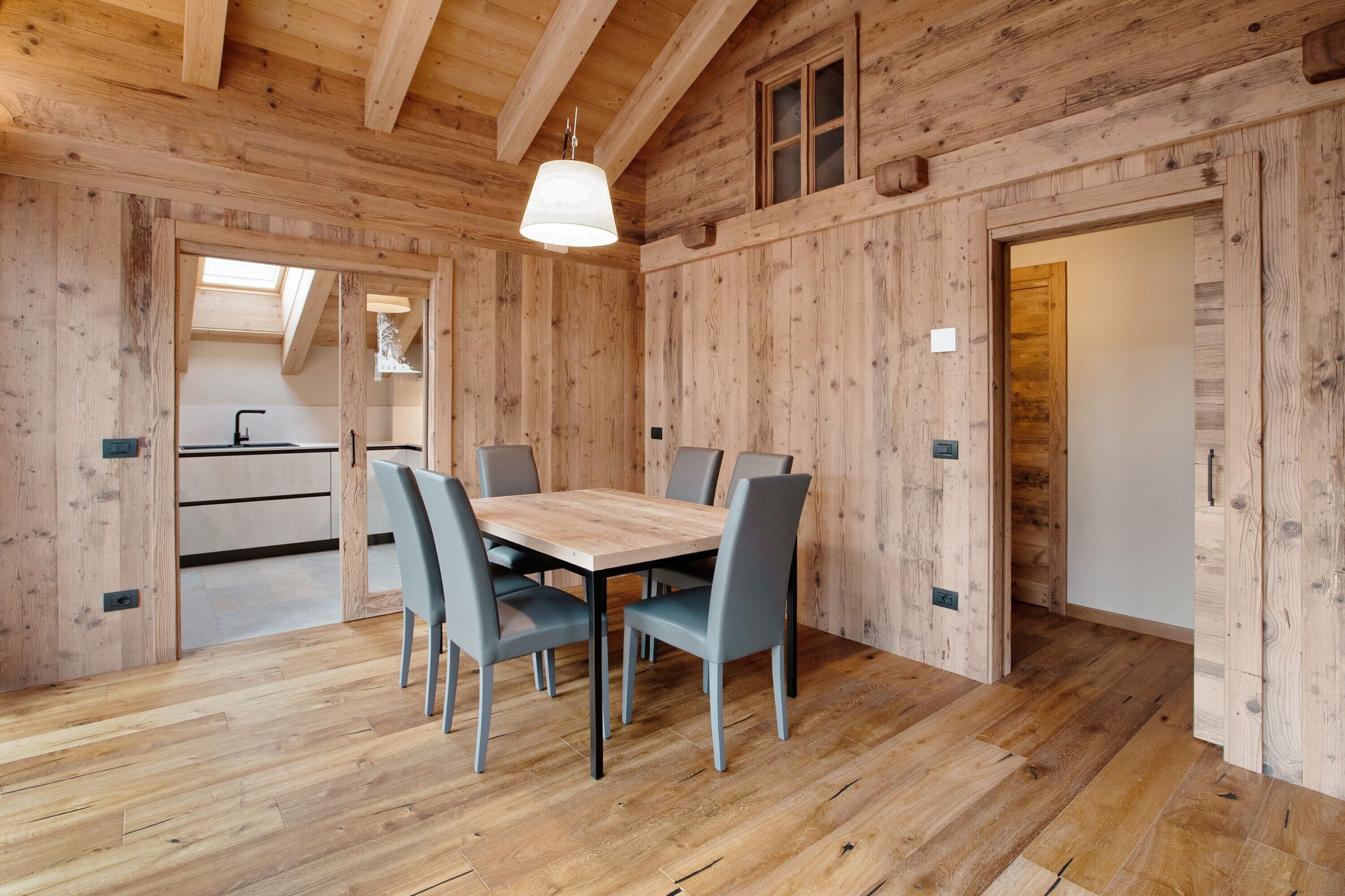 Un interior de madera con una mesa de comedor, sillas y una lámpara colgante.