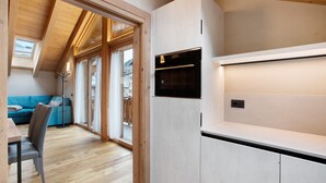 Une cuisine moderne avec des armoires blanches, un four noir et une lucarne.