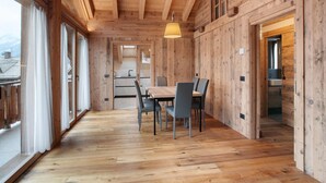 Un intérieur en bois comprenant un coin repas, de grandes fenêtres et une cuisine.