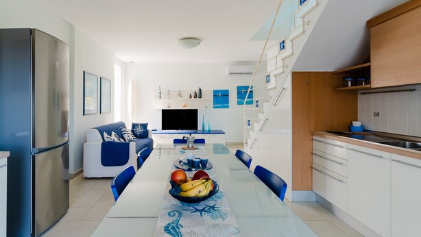 Una cocina moderna con comedor, horno empotrado y televisor.