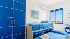 Un dormitorio con literas, una cama individual, una ventana con vistas y un armario azul.