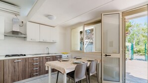 Una cocina moderna con comedor, una ventana con persianas y una puerta corredera de vidrio que da a un espacio exterior.